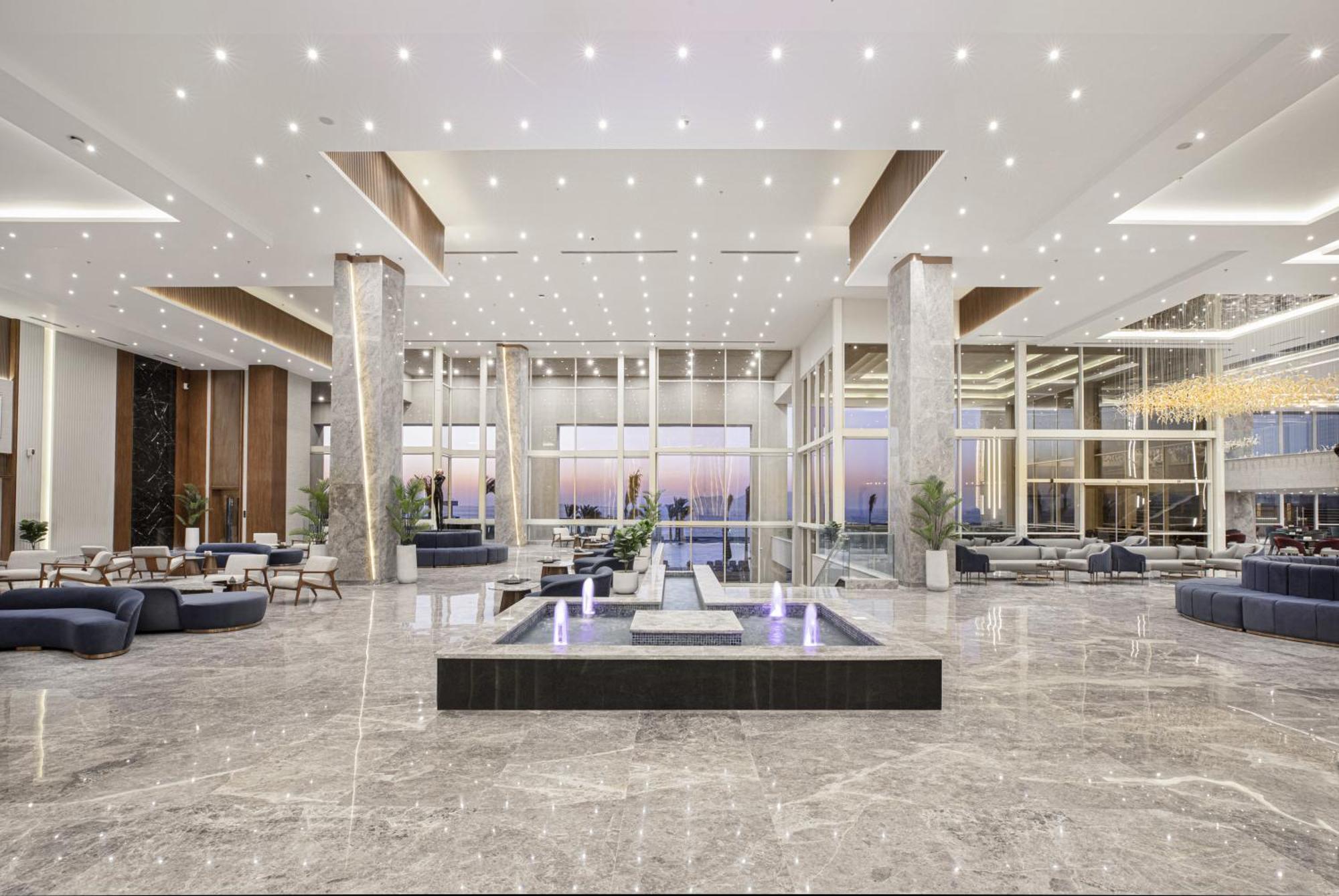 V Hotel Sharm El Shiekh Exterior photo The photo shows a modern and spacious lobby area. It features high ceilings with numerous recessed lights creating a bright atmosphere. The flooring is made of glossy marble, adding to the elegance of the space. 

In the center, there is a sleek wate