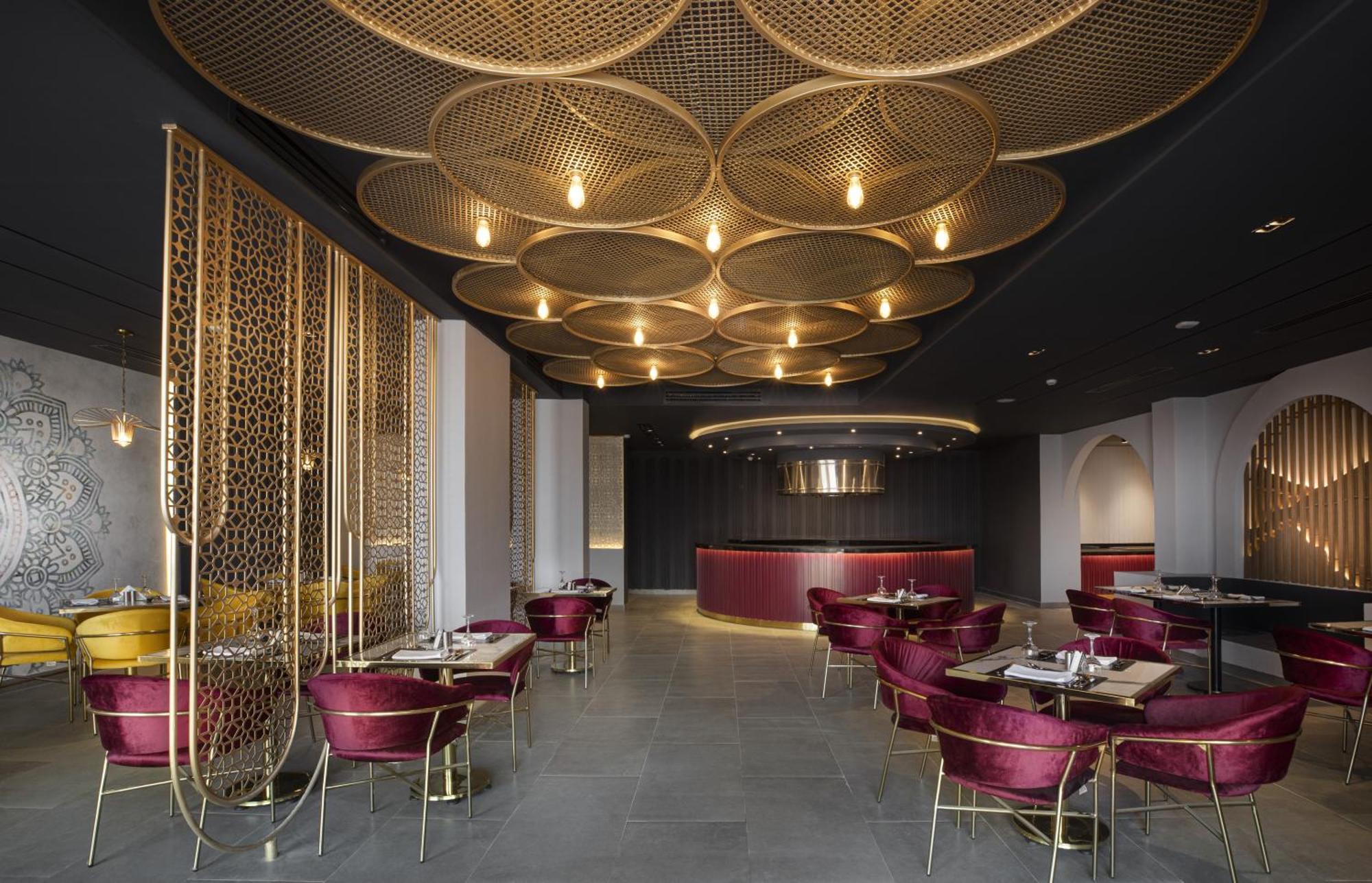 V Hotel Sharm El Shiekh Exterior photo The image shows a stylish and modern restaurant interior. The ceiling features a unique design with large, circular patterns that are illuminated by warm lighting. The walls are adorned with a sophisticated, dark color scheme complemented by elegant 