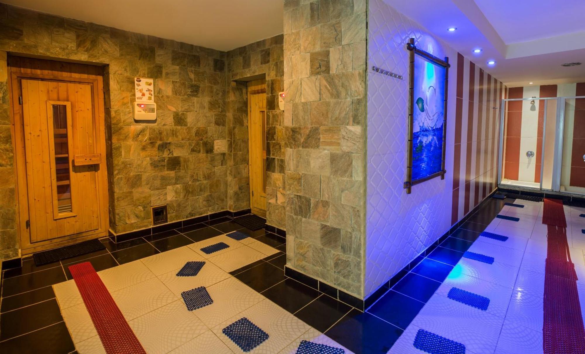 V Hotel Sharm El Shiekh Exterior photo The photo shows an interior space that appears to be a spa or wellness area. The walls are made of natural stone, giving a serene and earthy feel. There are wooden doors on one side, likely leading to sauna or treatment rooms. The floor has a unique 